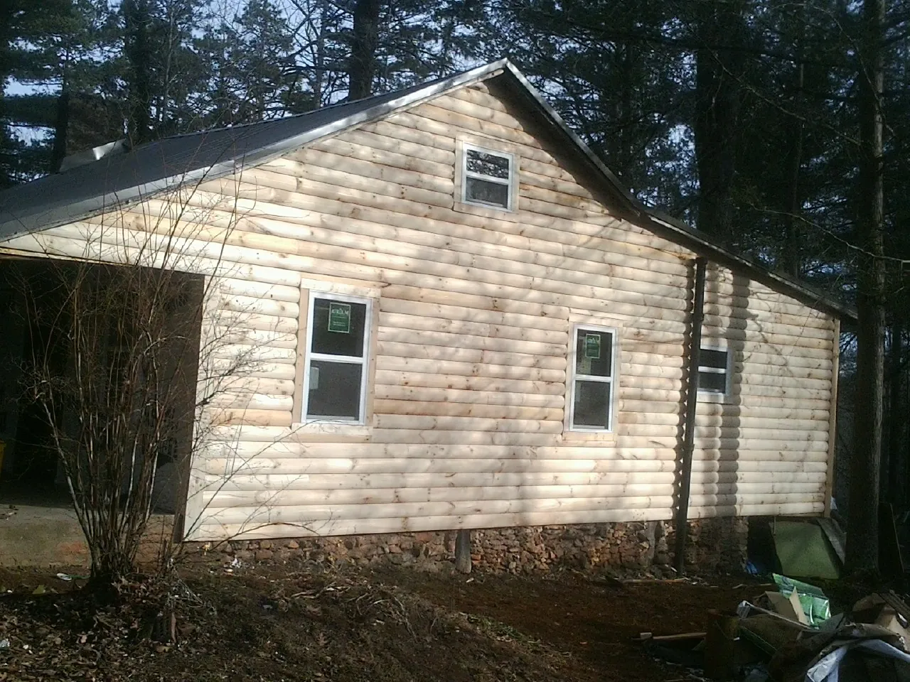 New log siding and dark metal roofing on a gable end in Brockton
