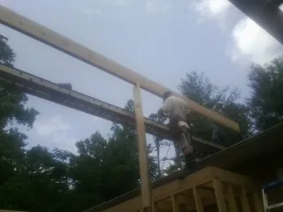 Carpenter setting a ridge beam over a new addition frame — Ice Dam Removal by Roofing Brothers in Brockton