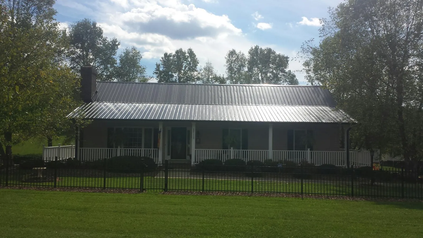 Gray metal roof on a brick ranch with a full width front porch — Gutter Guard Installation work by our crew in Brockton