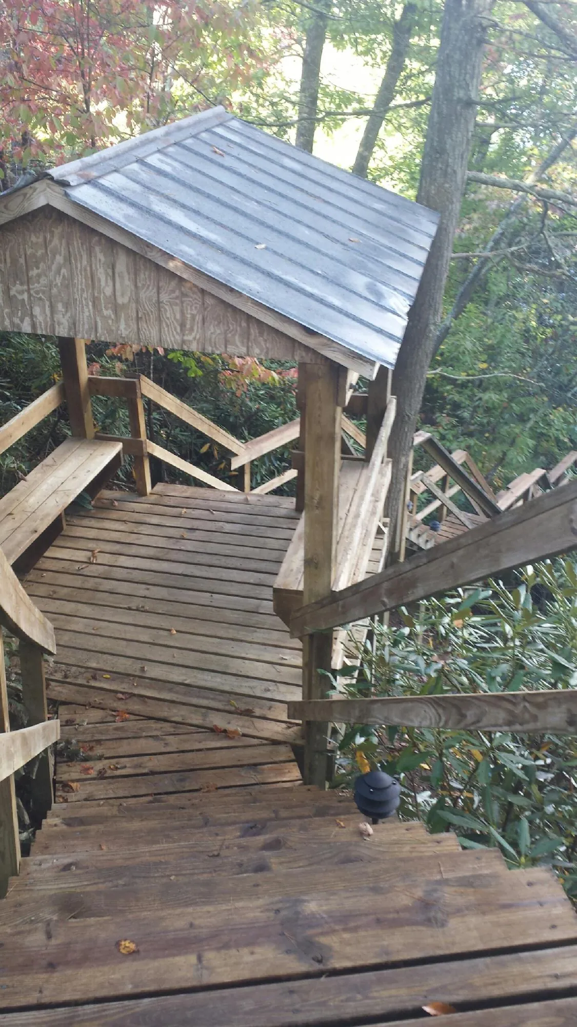 Metal roofed shelter over wooden steps on a wooded walkway — Skylight Repair & Installation work by our crew in Brockton