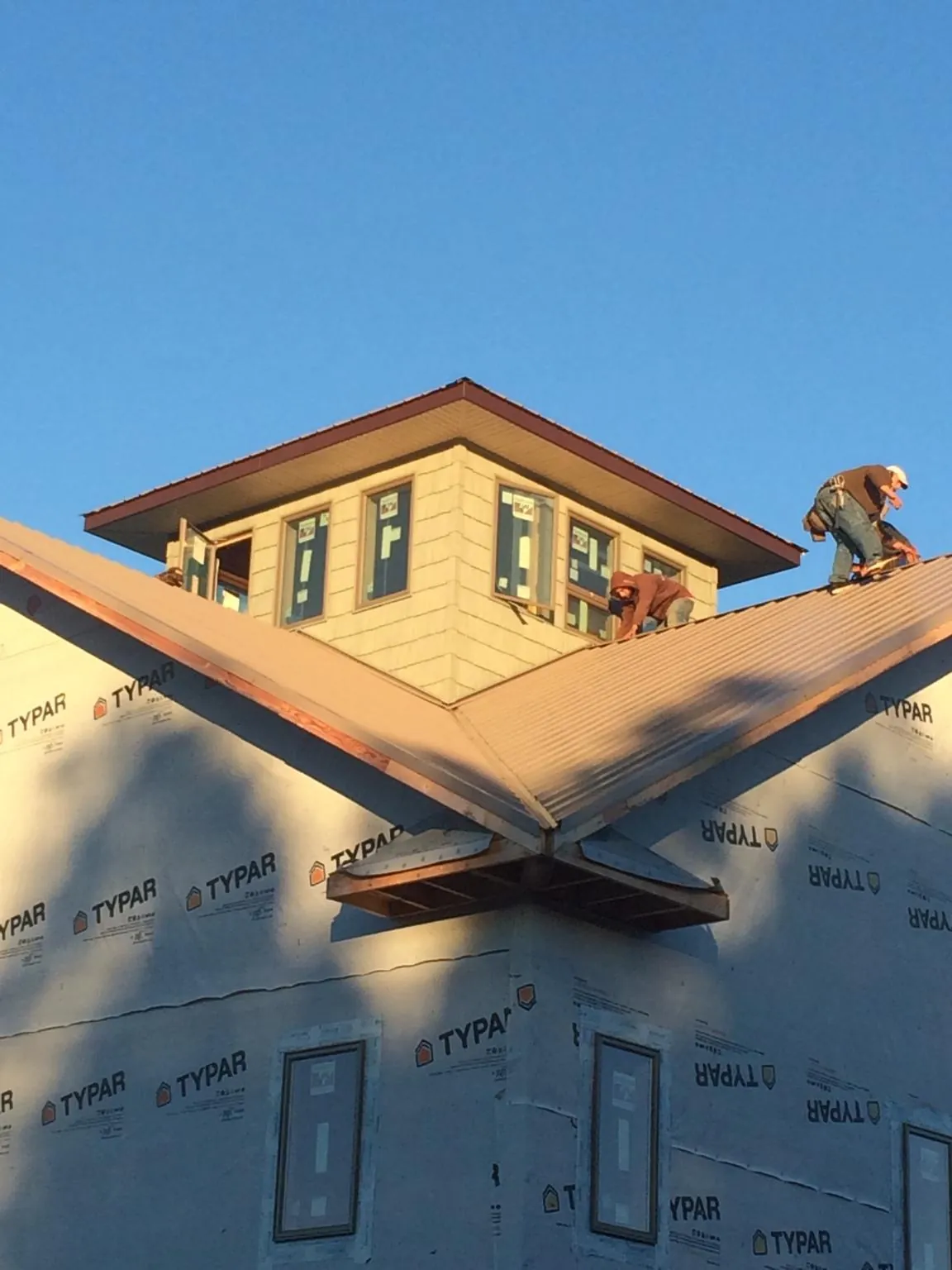 Roofers working around a rooftop cupola on a new metal roof at sunset — Roof Waterproofing in Brockton by Roofing Brothers